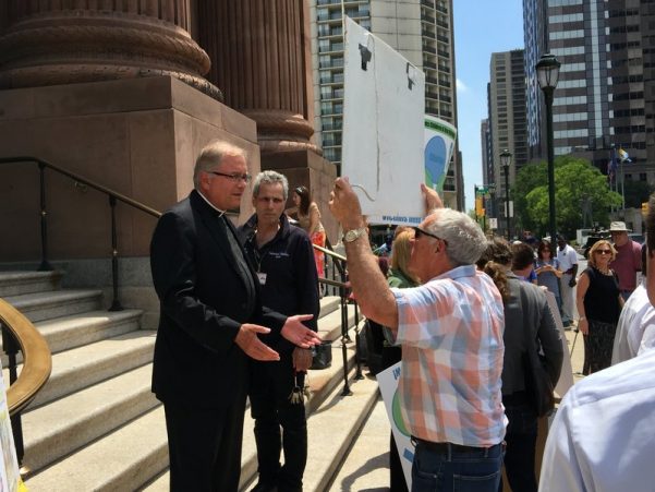 The Rev. Dennis Gill, rector and pastor of the Cathedral Basilica of Saints Peter and Paul, speaks to a protester before Monday afternoon's event got underway.